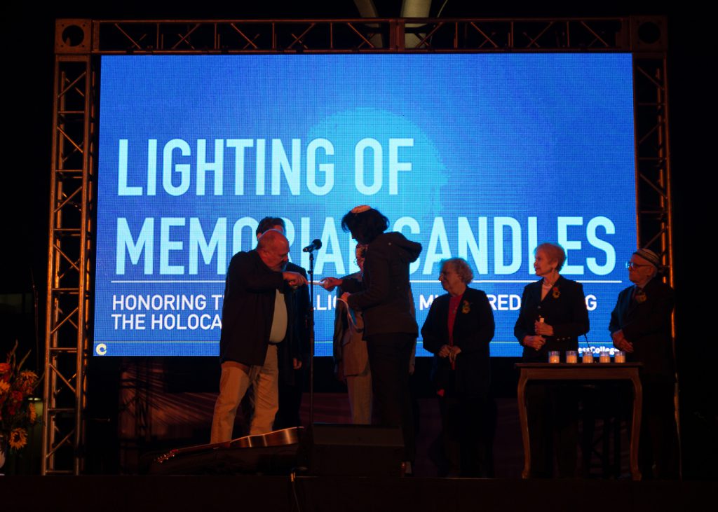 Men standing on stage lighting candles