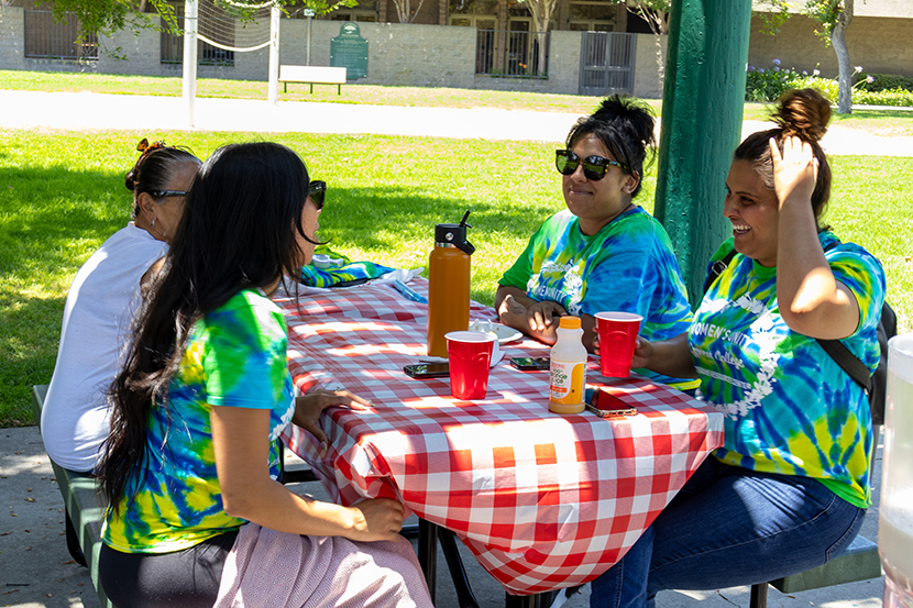 Four ladies gathered around a picnic table conversing