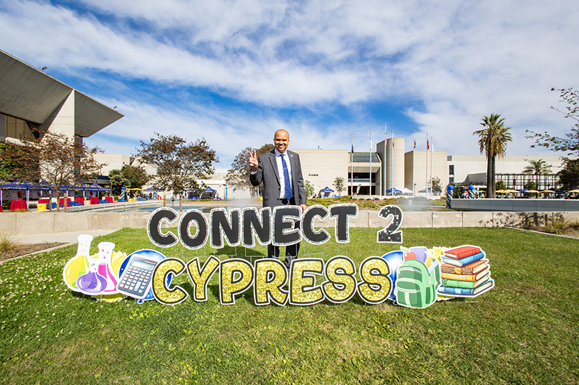 President Dr. Thayer stands behind the Connect 2 Cypress sign.