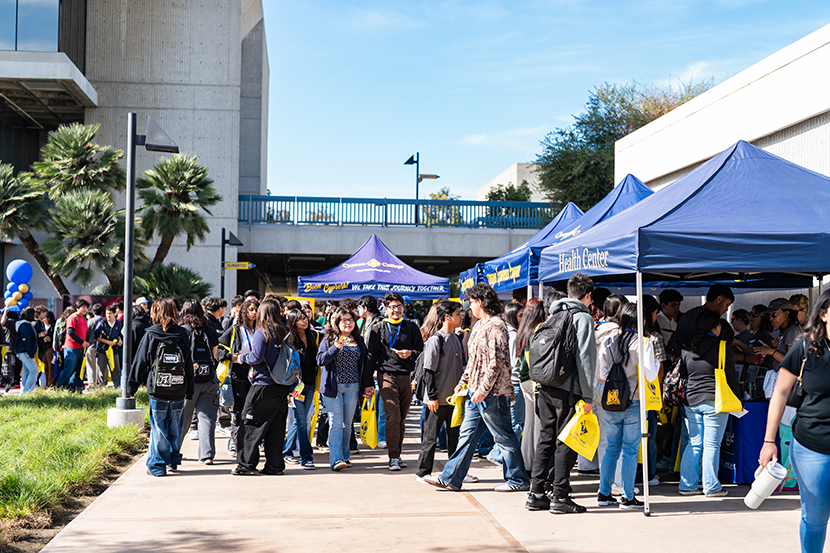 A diverse group of students gathered outside a Cypress College building, engaged in conversation and enjoying the outdoors.