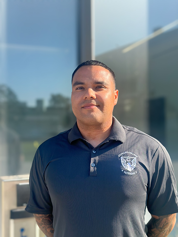 Benjamin Monroy, Adjunct Counselor, wearing a gray Cypress College Veterans polo shirt, standing in front of the VRC