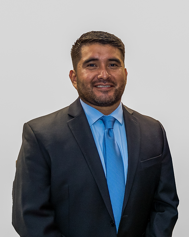 Dr. Juan Carlos Garcia, Veterans Resource Center Coordinator, wearing a dark suit with a blue shirt and tie, against a white background