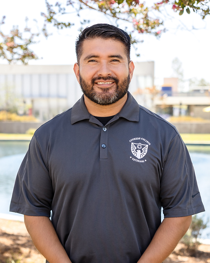 Dr. Juan Carlos Garcia, Veterans Resource Center Coordinator, wearing a dark suit with a blue shirt and tie, against a white background