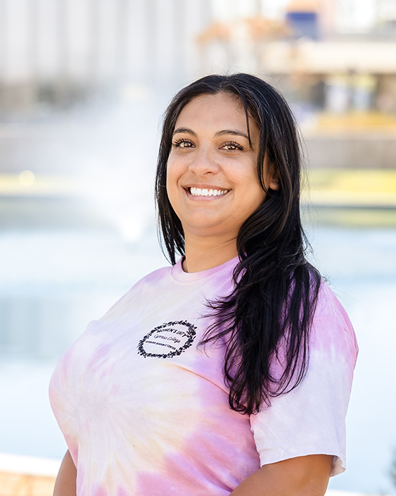 Natalie Navarette wearing a pink tie-dyed t-shirt with her long brown hair draped over her shoulder