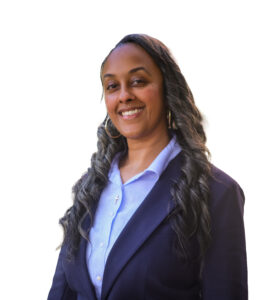 A woman with long hair in curls and a blue shirt with a blazer smiles for the camera.