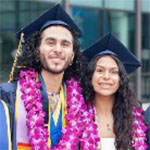 Man and woman in graduation regalia smiling