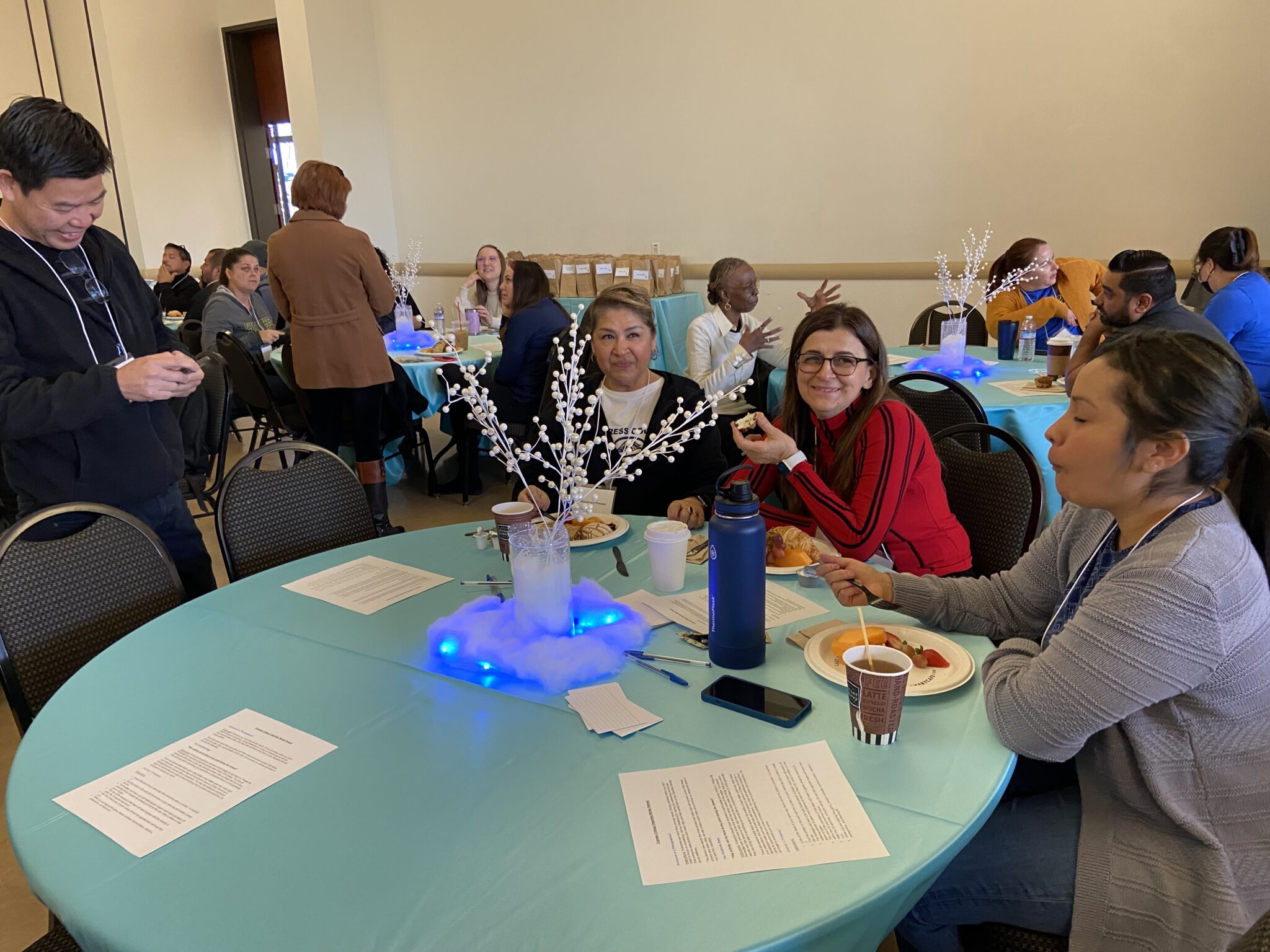 Classified staff enjoying breakfast as a colleague stops by.