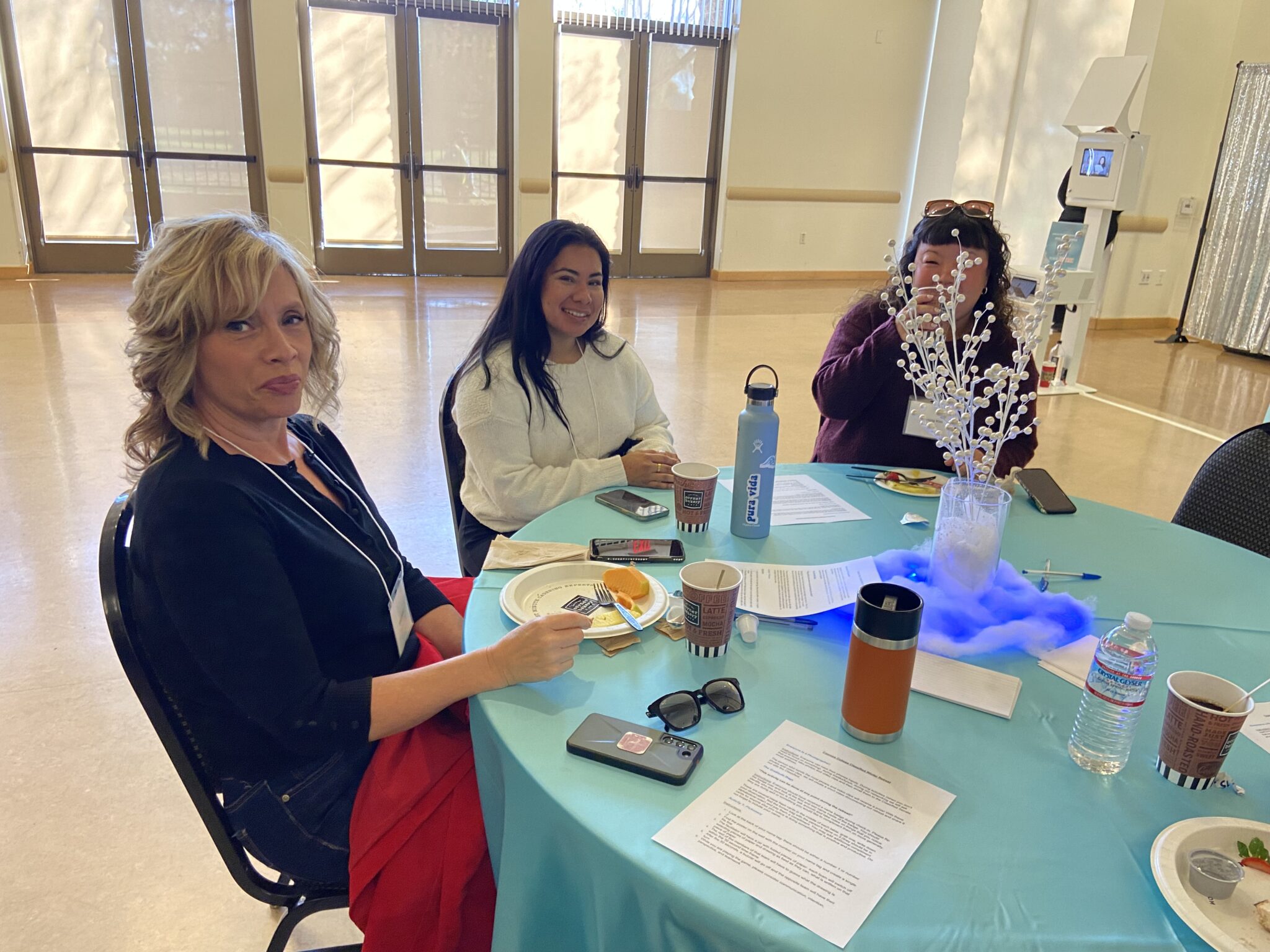 Three classified staff pose for a picture at their winter theme decorated table.