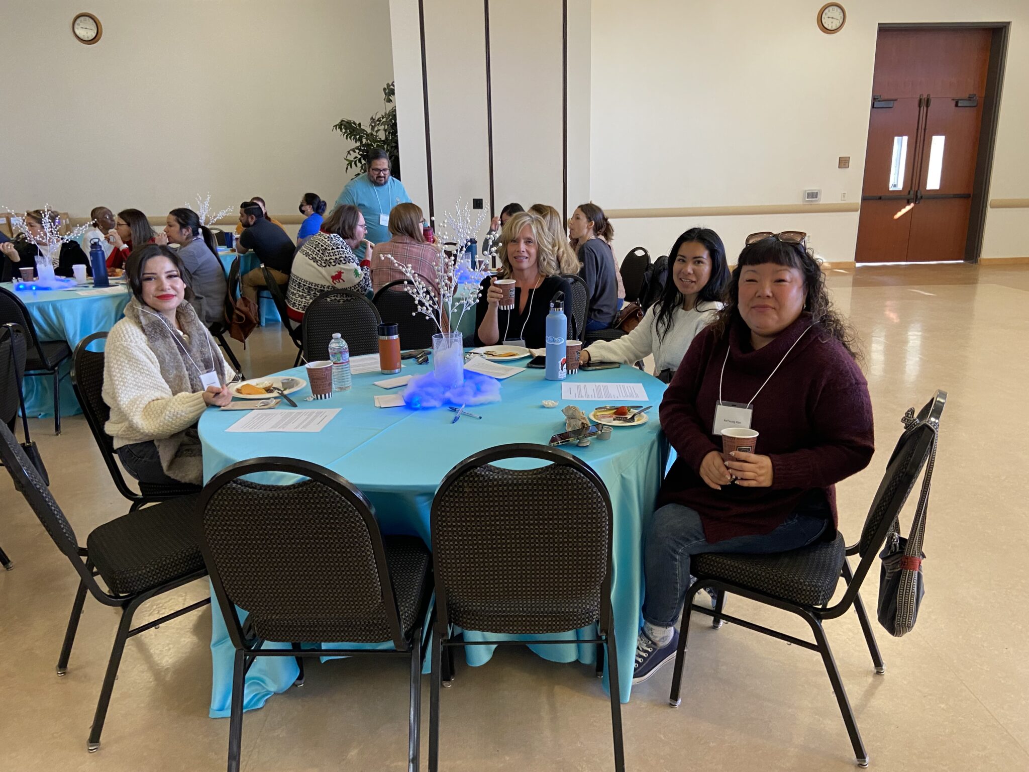 Four classified staff pose for a picture at their winter theme decorated table.