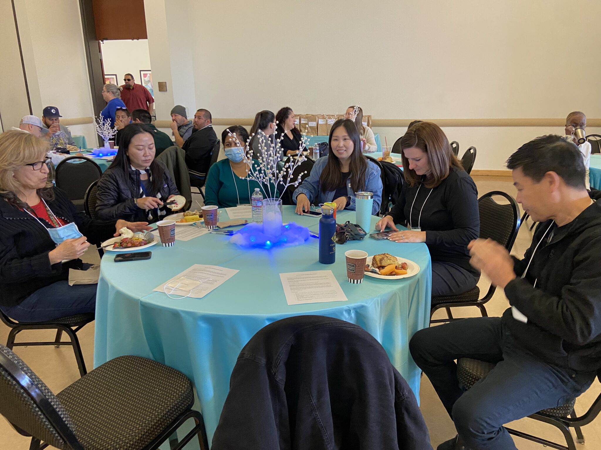 A group of classified staff sitting at a table participating in an activity using their cell phones.