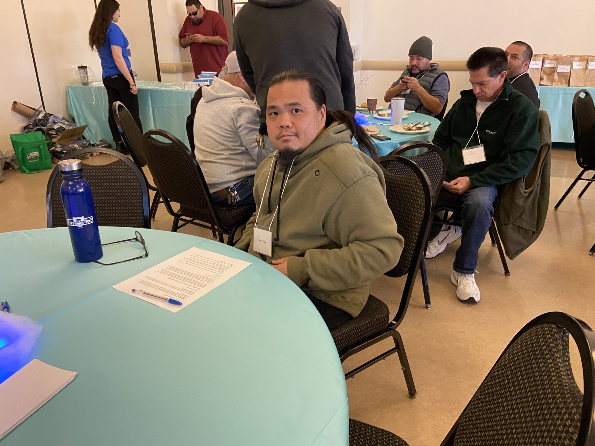 A classified staff member poses for photo while sitting at a table.