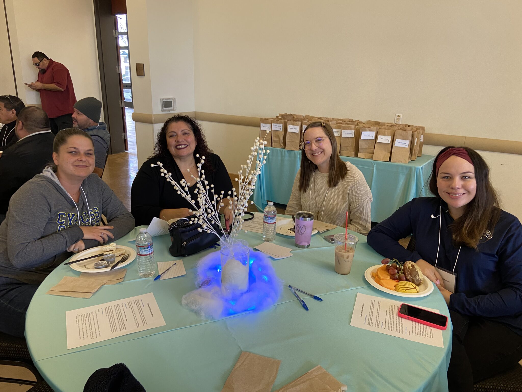 Four classified staff take a group photo at their winter themed table while enjoying their breakfast.