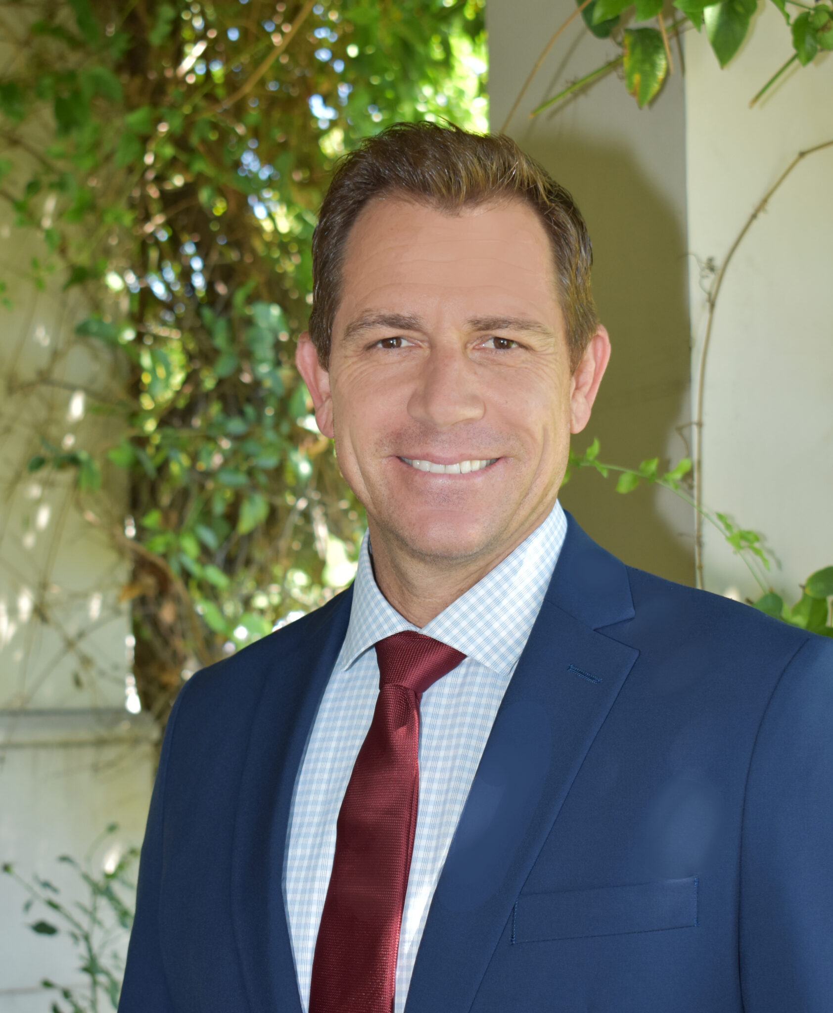 Portrait of Aaron France in a blue suit with a red tie