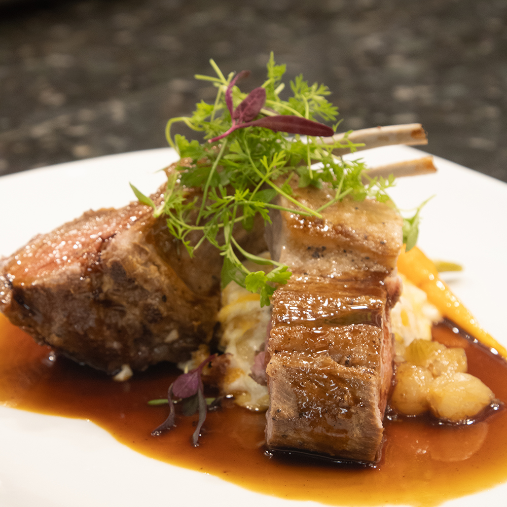 A plated meal at the Cypress Bistro made up of meat, potatoes, and garnish.