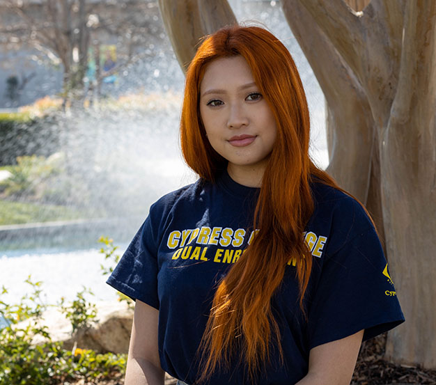 Dual Enrollment staff Megan Cao with long red hair and pond in background