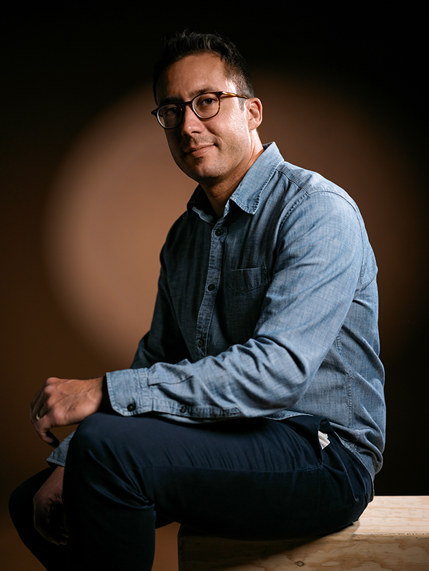 Professional photo of Ashton Politanoff sitting in a dim light