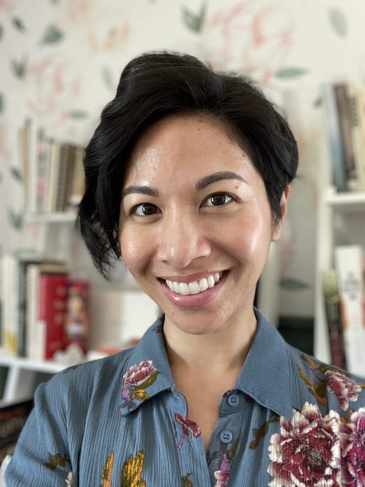 Professional headshot of Stephanie Tran smiling in a blue floral blouse against a softly blurred indoor background.