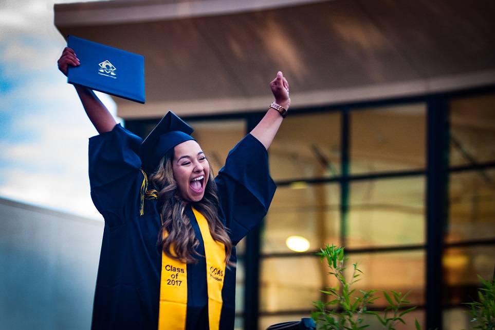 Student at graduation holding up diploma