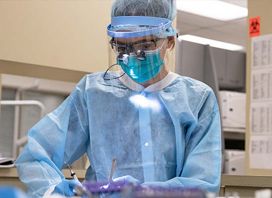 Student wearing personal protective equipment while working on teeth