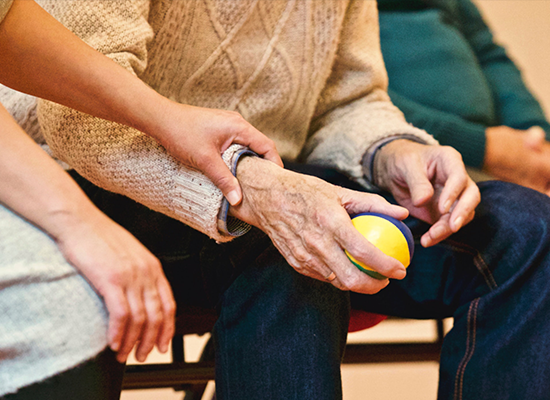 Younger person holding the arm of an older person who is holding a ball