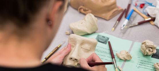 Student working on a clay model of a face