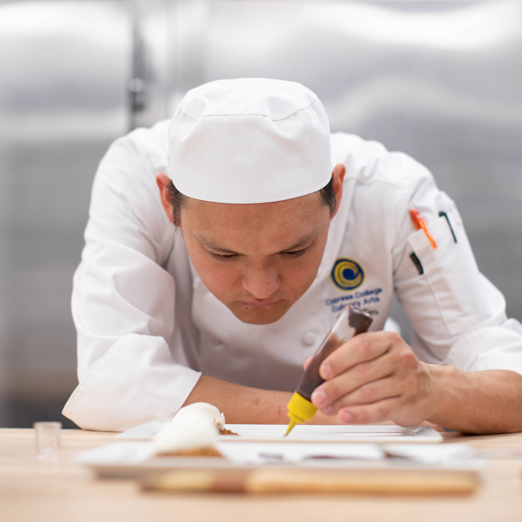 Instructor Dan Kim examines a dish he created.