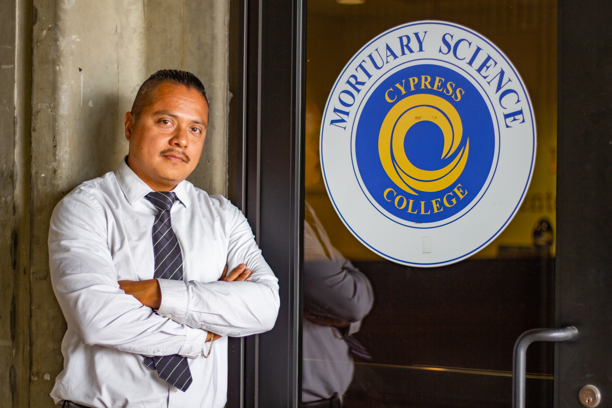 David Garcia stands in front of the Mortuary Science department sign.