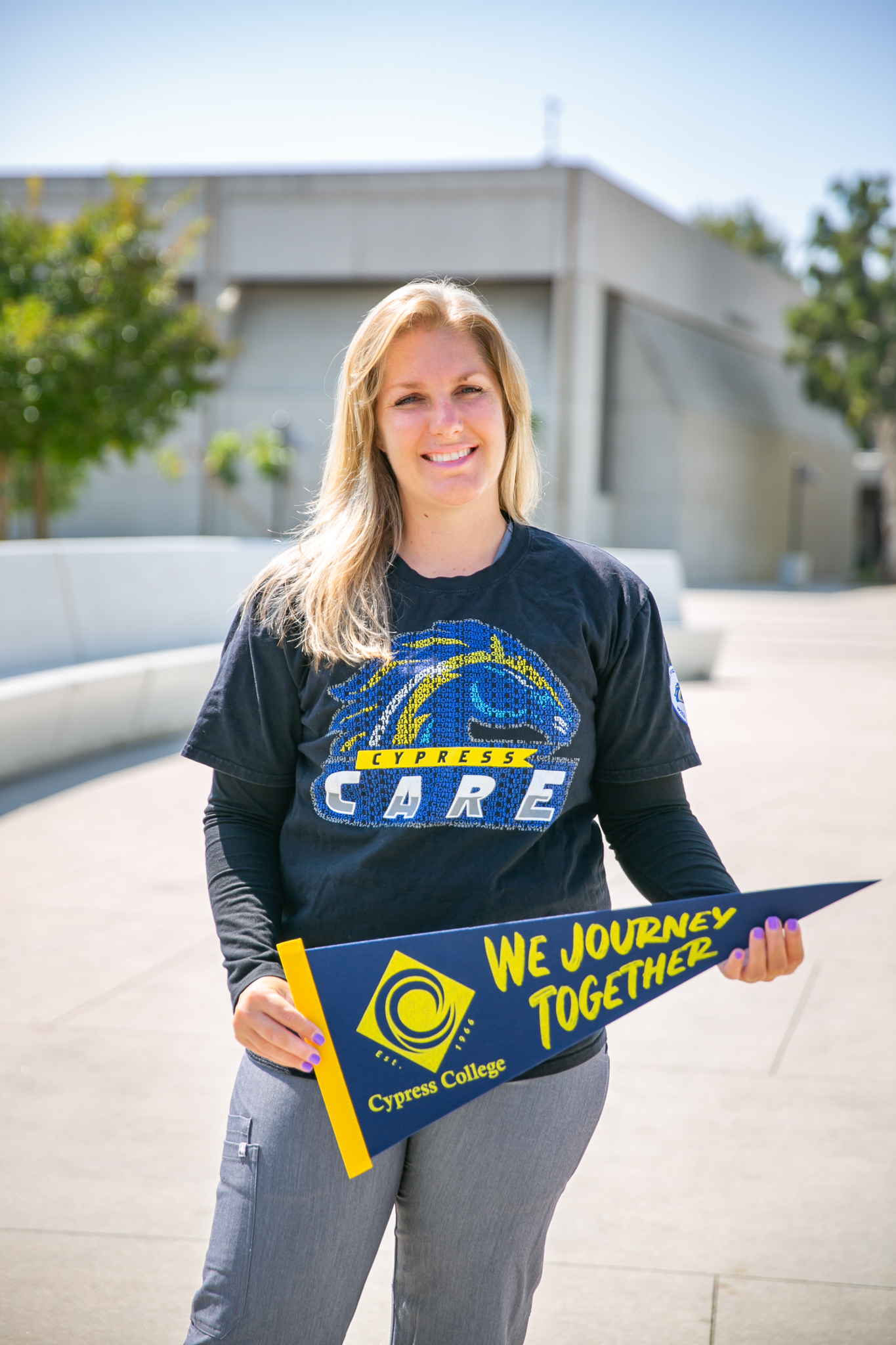 Emily Costello holds a Cypress College pennant as she stands on the memorial bridge on campus.