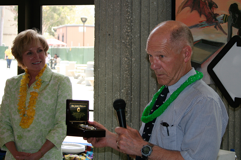 Older man in a blue checkered shirt holds microphone while woman smiles