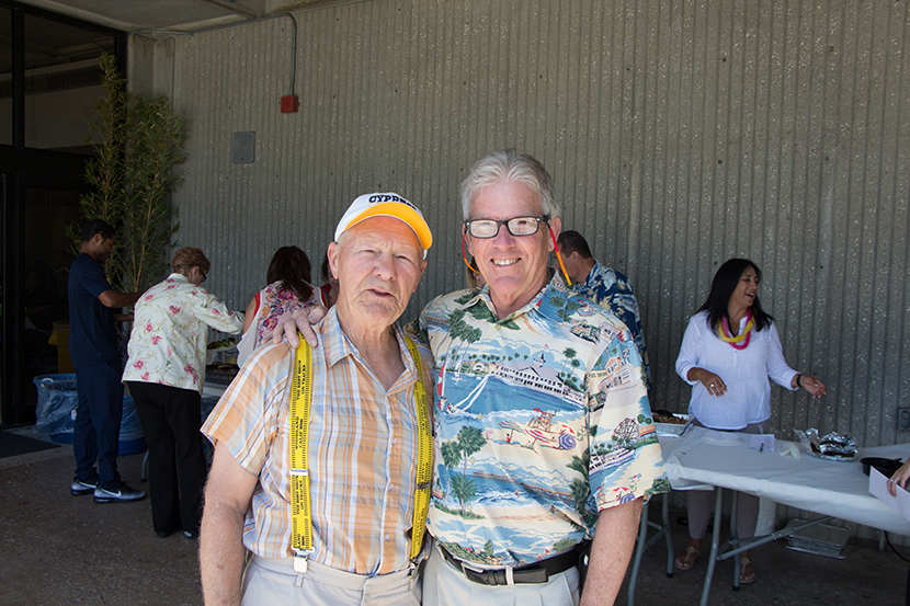 Two men stand together, smiling