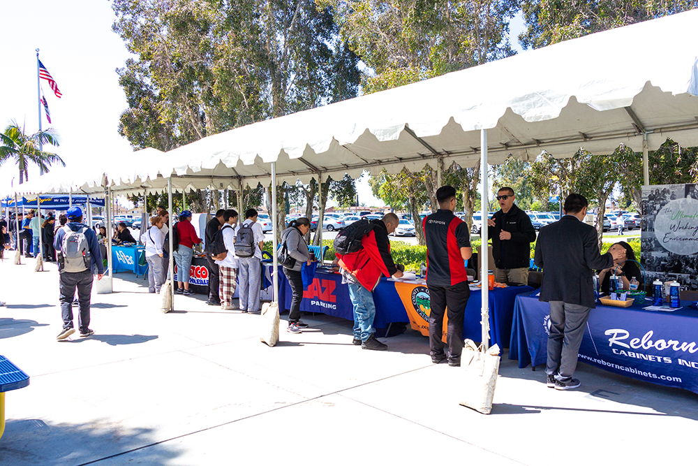A line of Career Fair information tables have students in front of each one.