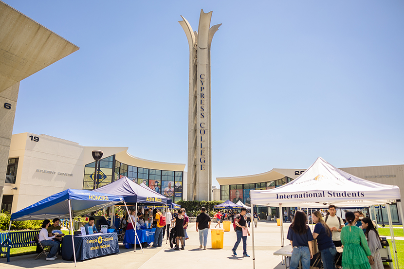 Students gather in Gateway Plaza. Booths and the campanile are visible in the background