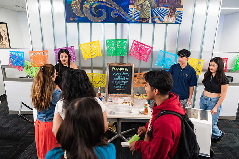 Students gathered at Puente Center with colorful banner and signs in the background