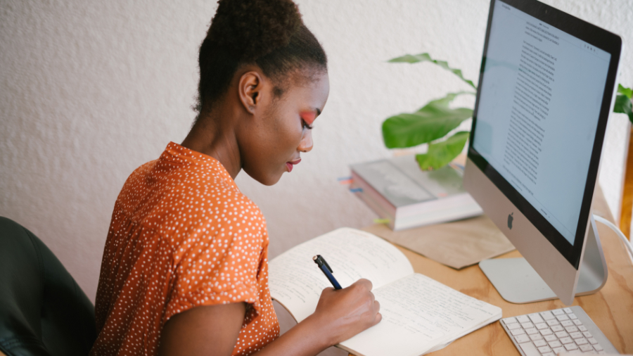 Woman taking notes by a computer