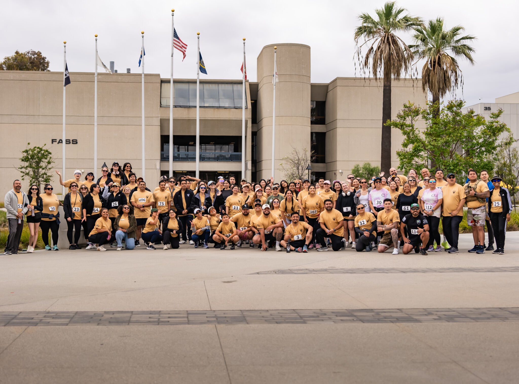 Participants in 5K, about 80 of them, pose in their racing shirts and numbers.