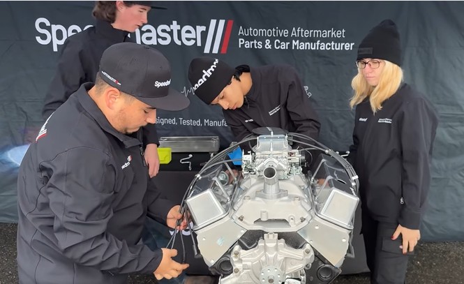 Four students work on a car engine 