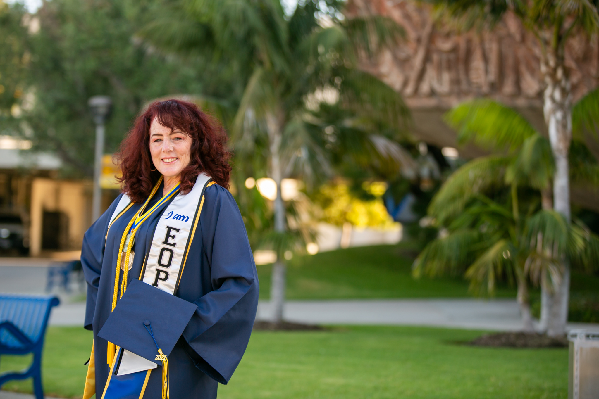 Lisa Plechner poses in graduation regalia outside a Cypress College building.