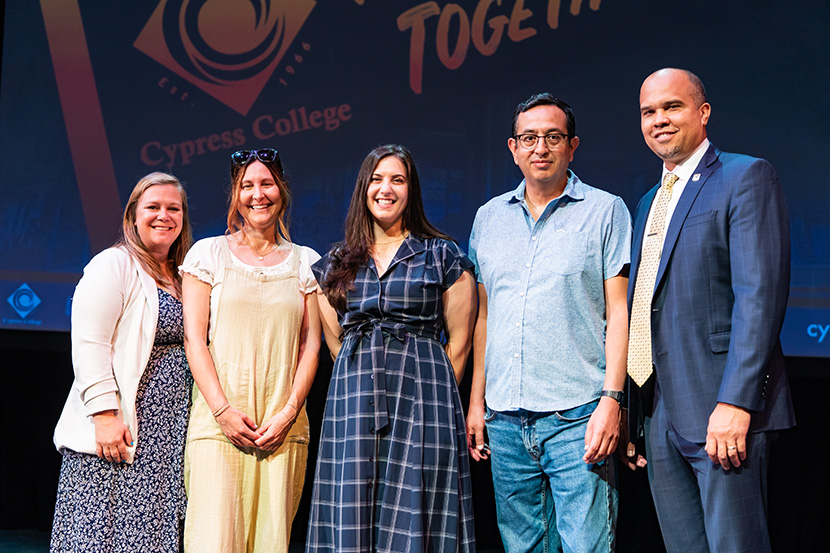 Five people smiling and standing together on stage at a Cypress College event.