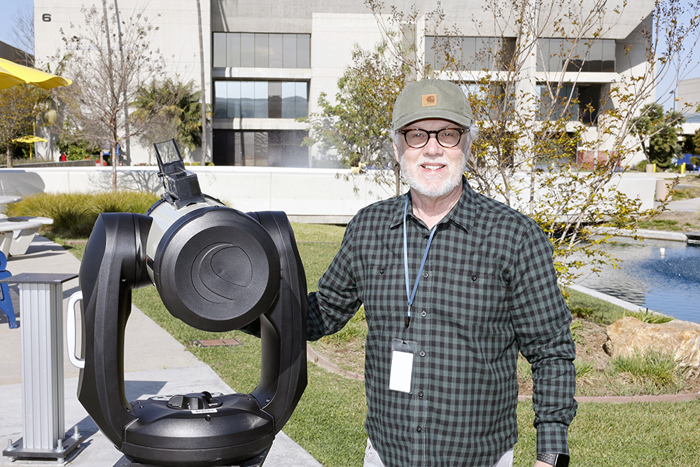 Professor Michael Frey stands with telescope on campus.