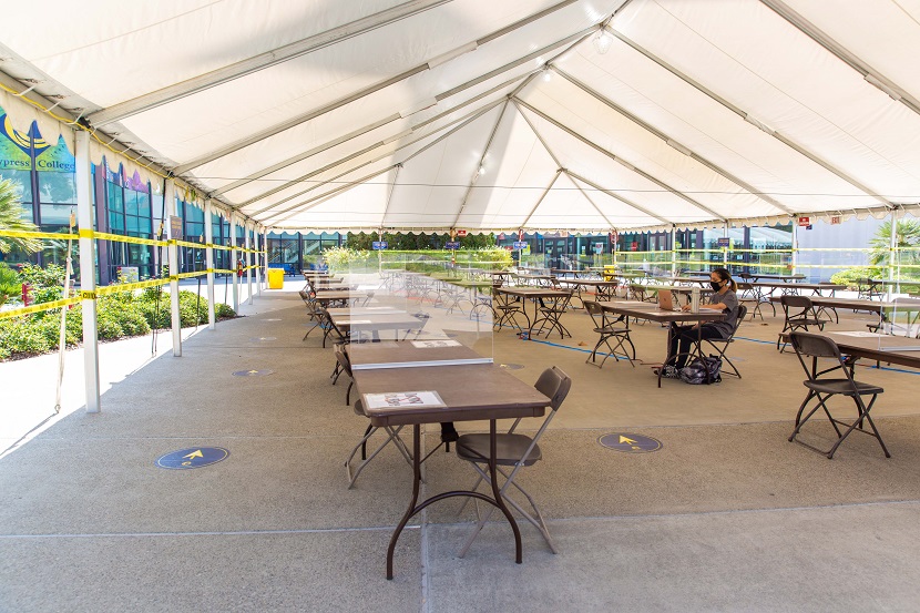Tent with tables and chairs and a student studying