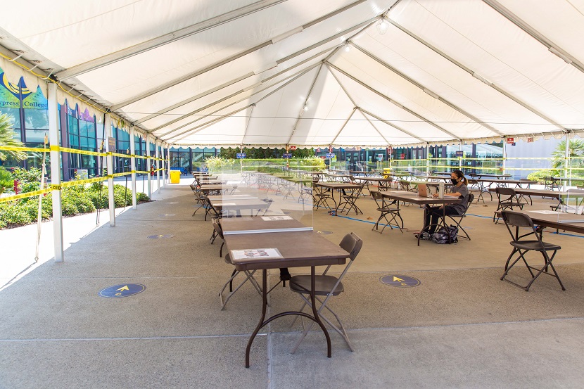 Tent with tables and chairs and a student studying