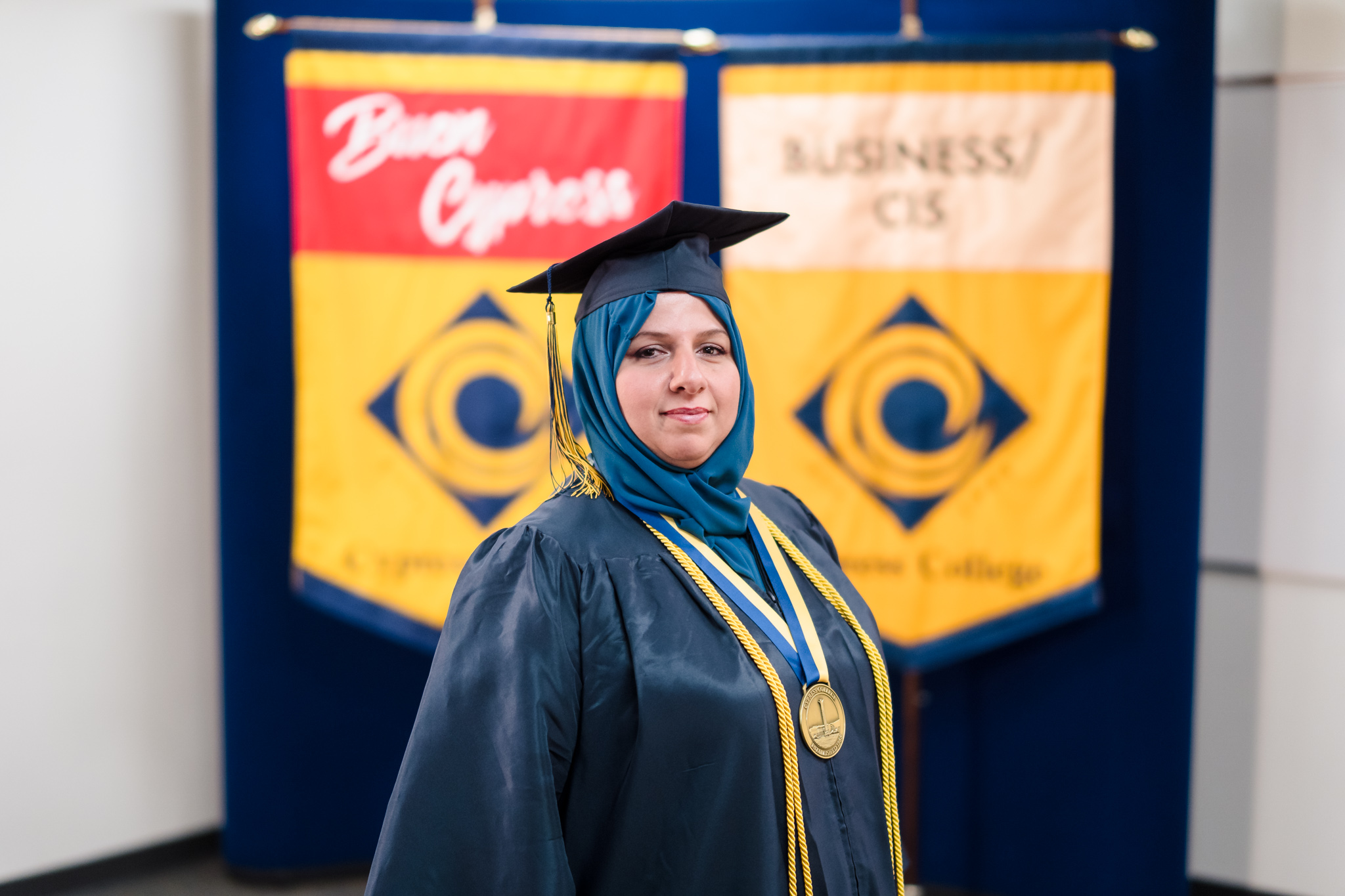 Student Rasha Jasim poses in front of the Cypress College pond wearing graduation regalia.
