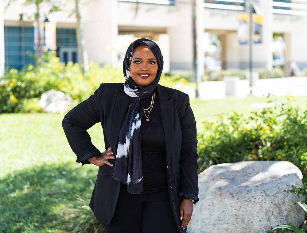 A woman in a head scarf smiles at the camera.