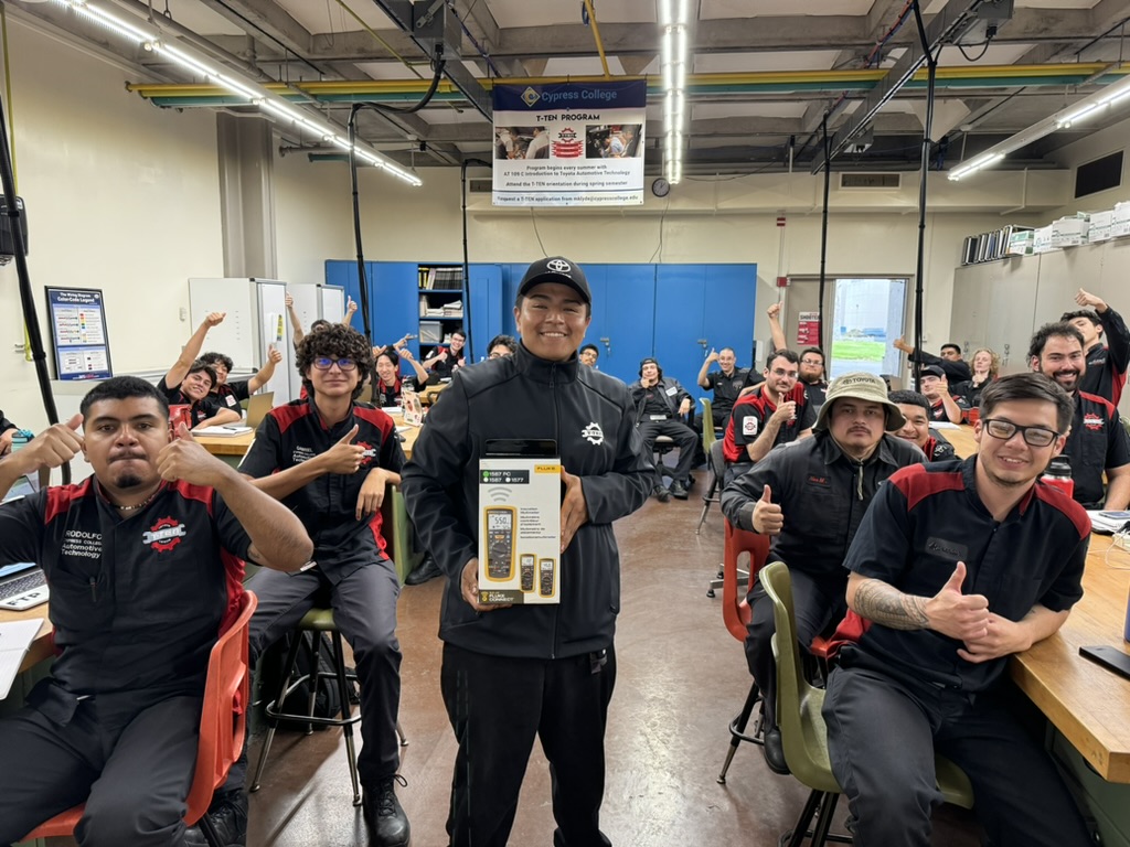 Jesus Salgado holds an award in an automotive technology classroom surrounded by fellow T-TEN students giving him a thumbs-up.