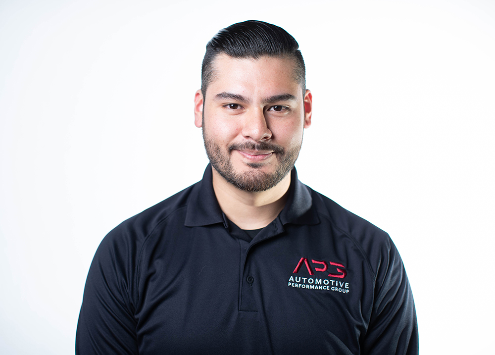 A young man in a black polo shirt smiles at the camera.