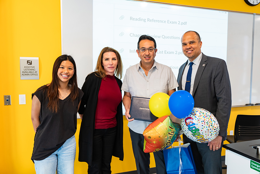 A student, two instructors, and the college president pose to honor Francisco Perez (second from right) with Teacher of the Year nomination.