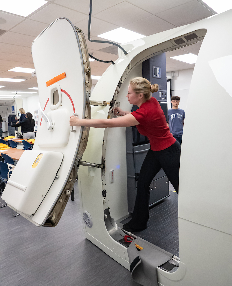 A student opens an airplane exit