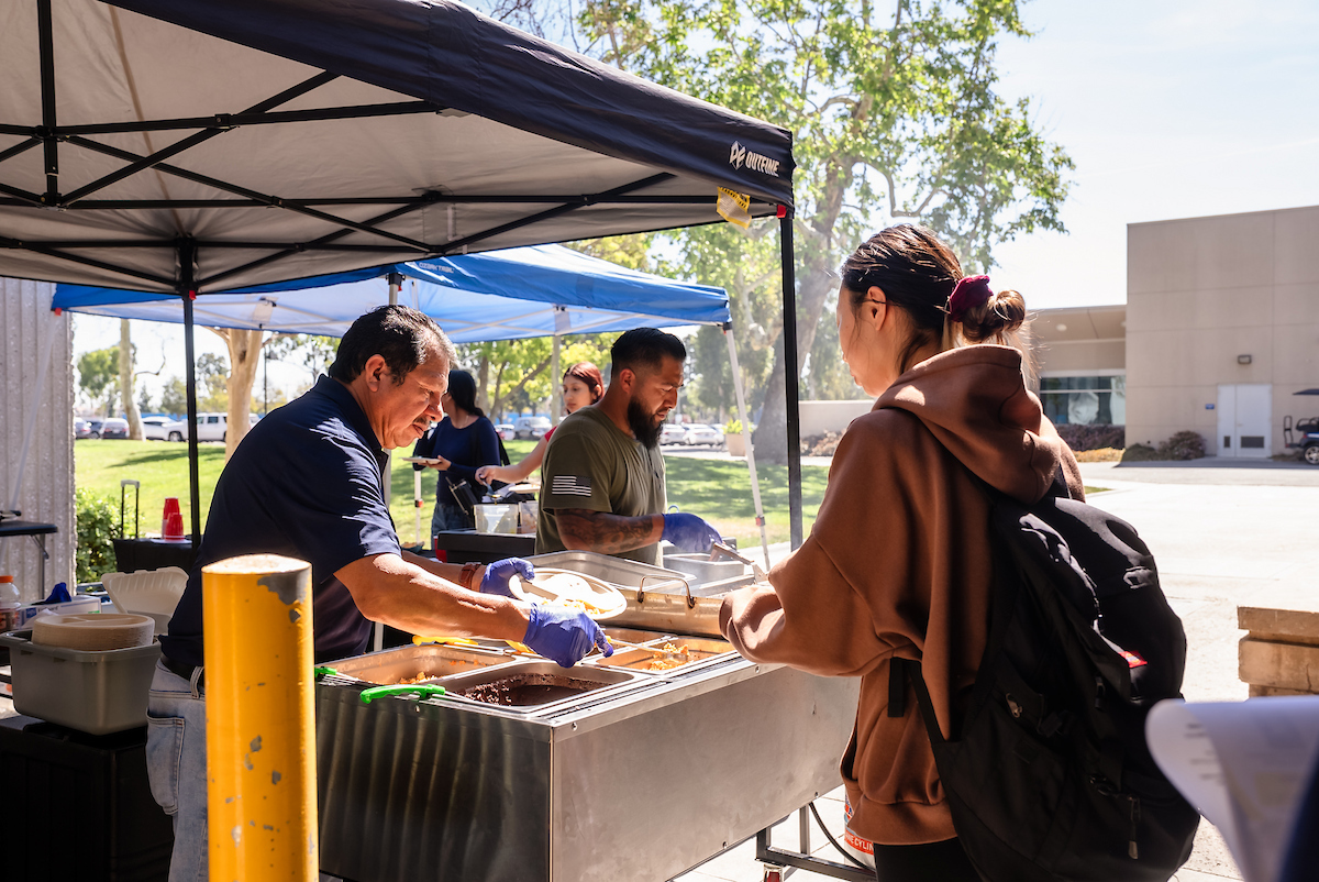 A student waits for food at an outdoor taco bar.