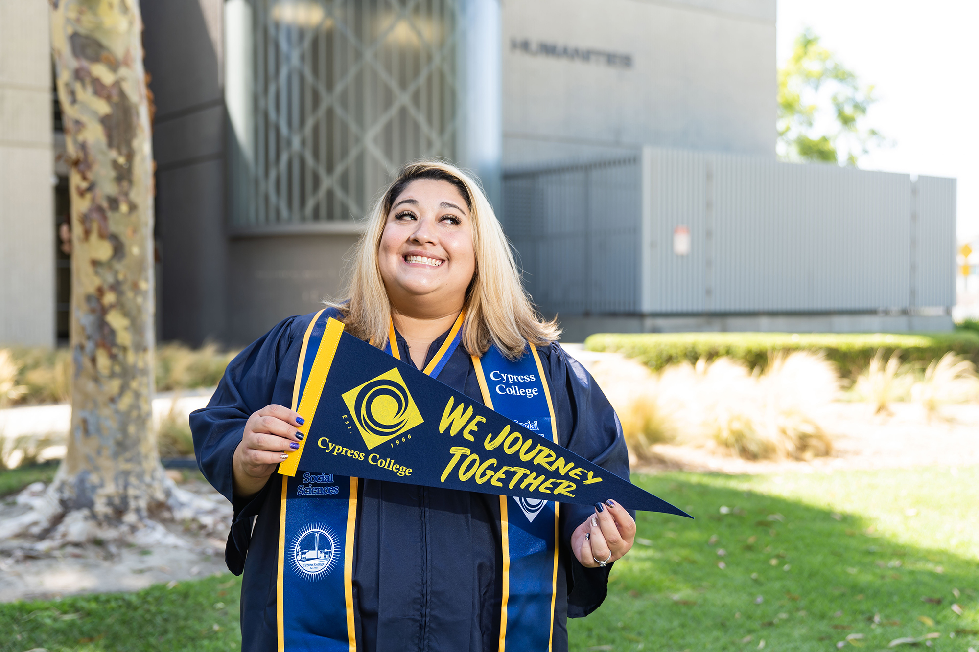 A woman with a bright smile holds a pennant that says "We Journey Together."