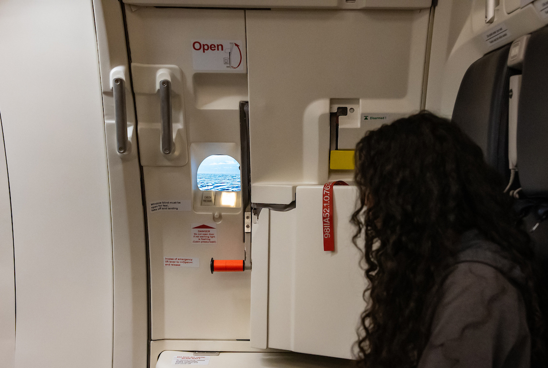 A student looks out the window of a simulated airplane